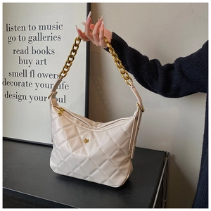 Detail of beige quilted hobo bag with gold flower logo and chunky chain strap