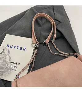 Close-up of pink tote bag with dual leather and chain shoulder straps on a grey suit