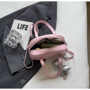 Detailansicht einer rosa Tasche mit Smartphone und grünem Portemonnaie im Inneren
