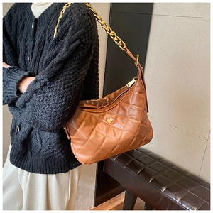 Detail view of caramel brown quilted hobo bag with vintage gold chain strap and floral logo