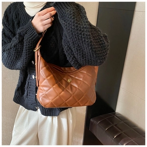 Detailed view of brown quilted leather bag with elegant golden flower metal buckle