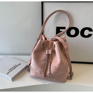 Detailed close-up of pink bucket bag with suede texture, chain strap, and drawstring closure