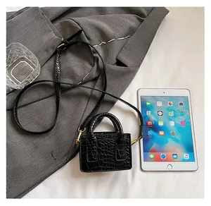 Mini black crocodile texture handbag shown next to an iPad for size comparison