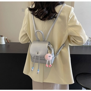 Mini zaino argento metallizzato con ciondolo in peluche rosa indossato da modella