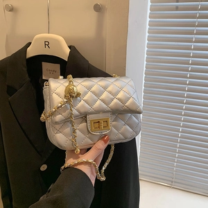 Silver quilted leather chain bag with golden ball adjuster shown in hand with black blazer