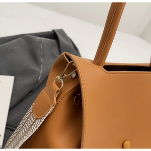 Detail der braunen Handtasche mit goldener Metallschnalle und gewebtem Schultergurt