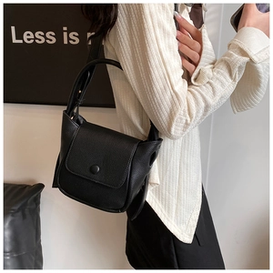 Close-up of black lychee texture leather shoulder bag with chic flap and wide strap