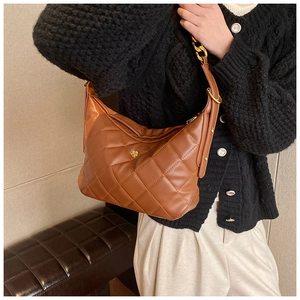Detail of brown quilted leather bag with gold flower logo and chain shoulder strap