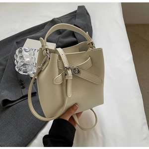 Detailansicht der cremefarbenen Beuteltasche mit Lederstruktur und Metalldrehverschluss