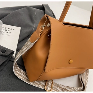 Detail der karamellfarbenen Ledertasche mit Schnalle und gewebtem Schultergurt