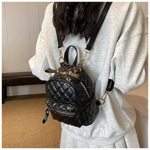 Detail of black quilted mini backpack with leather bow and golden zippers on model