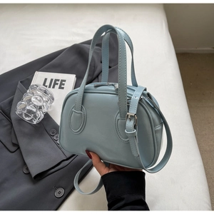 Detailansicht einer hellblauen Muschel-Handtasche aus glänzendem PU-Leder mit Silberbeschlag