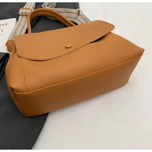 Nahaufnahme der karamellbraunen PU-Handtasche mit breitem Webriemen und Dekoschnalle