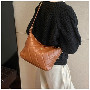 Brown quilted shoulder bag with gold floral clasp shown on model in a casual setting