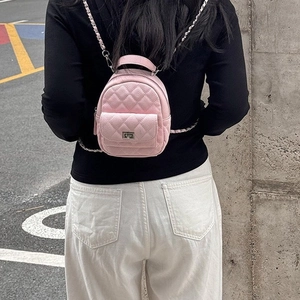 Pink mini quilted backpack with chain straps and silver twist lock on street background