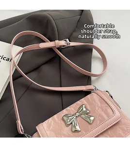 Close-up of pink bucket bag with silver butterfly buckle and adjustable strap
