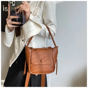 Detail view of brown lychee texture leather bag with drawstring and magnetic flap closure