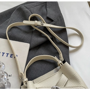 Detailaufnahme der beigen Eimer-Handtasche aus genarbtem Leder mit silberner Schnalle