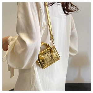 Detail of golden mini crossbody bag featuring crocodile embossed texture and metallic finish