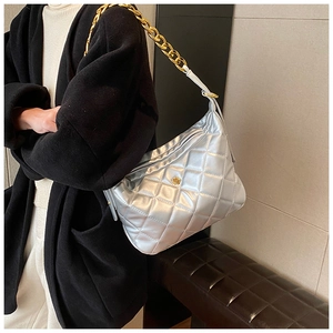 Detailed shot of silver quilted bag featuring a gold chain strap and floral logo