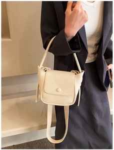 Close-up of litchi texture on a cream white leather crossbody bag with flap closure