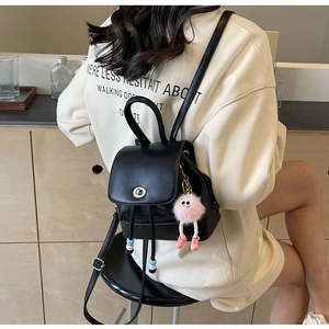 Dettaglio mini zaino in pelle nera con chiusura a scatto e ciondolo di peluche rosa