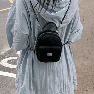 Mini black quilted leather backpack with silver chain straps shown on a model