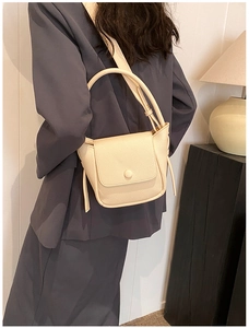Detail of creamy white litchi pattern leather shoulder bag on grey suit