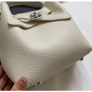 Detail der Eimer-Tasche aus Leder mit Lychee-Muster, silbernem Drehverschluss und Bodennägeln