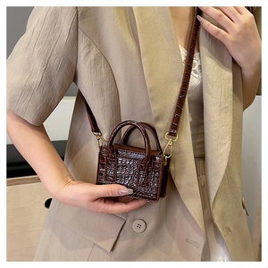 Detail of dark brown croc-textured mini bag with gold hardware and fine stitching