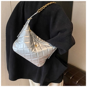 Detailed view of silver quilted shoulder bag with gold floral hardware and chain strap