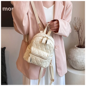 Detail of cream quilted mini backpack with gold zippers and diamond lattice stitching