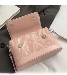 Detail of light pink wrinkled patent leather bag showing silver magnetic snap and interior