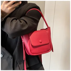 Detail view of red lychee grain leather handbag with stylish flap and round buckle strap