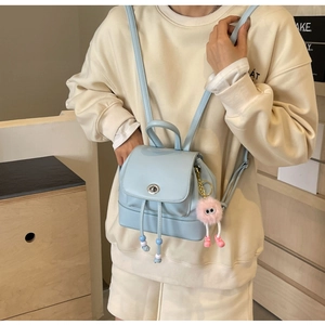 Dettaglio mini zaino azzurro con chiusura a rotazione in metallo e ciondolo di peluche