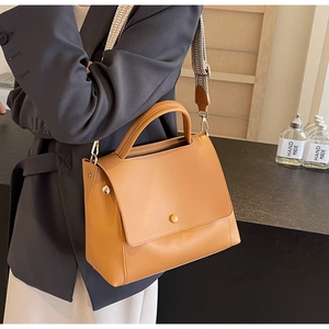 Detail einer braunen Lederhandtasche mit einem gewebten Vintage-Schulterriemen