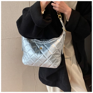 Detail of silver quilted handbag with golden chain strap and floral metal clasp