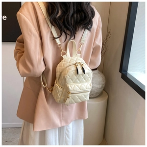 Detail view of mini quilted backpack in beige leather with adjustable gold chain straps