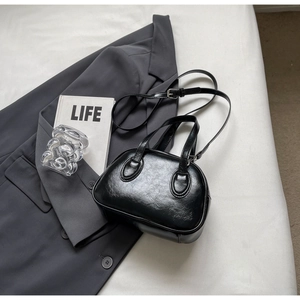 Details einer glänzenden schwarzen PU-Lederhandtasche mit Doppelgriffen auf einem Anzug