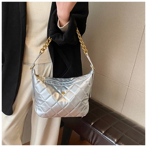 Detail of silver quilted shoulder bag featuring gold chain strap and floral hardware