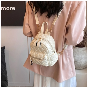 Detail of quilted mini backpack in cream faux leather with gold zippers and side pockets
