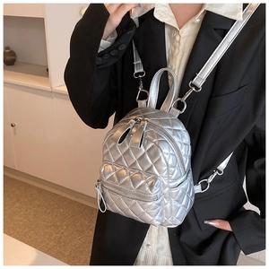 Silver quilted mini backpack detail showing metallic finish and diamond stitching on model