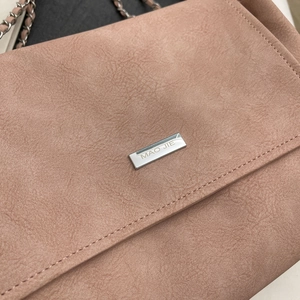 Detailed macro shot of the mauve leather texture and silver logo plaque on the chain bag