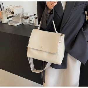 Detail einer cremebeige Handtasche mit stylischem, geometrisch gemustertem Schultergurt