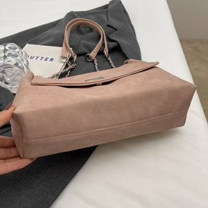 Detail of dusty pink leather tote bag with silver chain strap and metal clasp detail