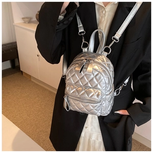 Detail of silver quilted mini backpack with metallic finish and adjustable thin straps