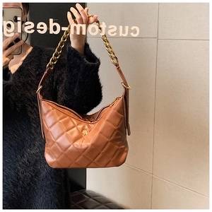 Detailed view of brown quilted hobo bag with vintage gold chain and flower accent