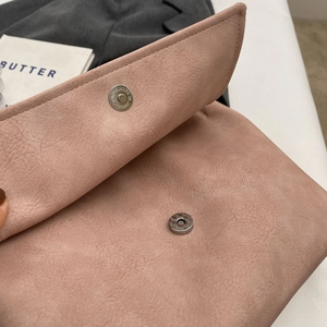 Detail of magnetic snap closure and suede-like texture on a dusty rose tote bag