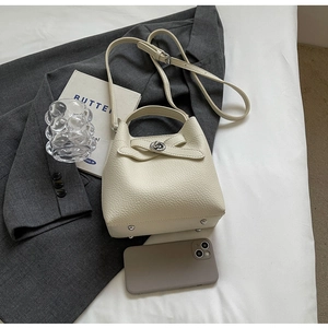 Detail der cremefarbenen Beuteltasche mit Lychee-Leder, Metalldrehverschluss und Silbernieten