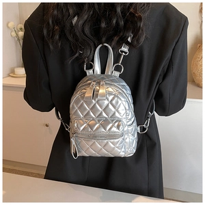 Silver quilted mini backpack shown on back of model wearing a black blazer for travel